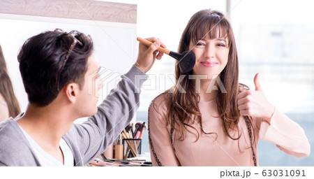 Man doing make-up for cute woman in beauty salon 63031091