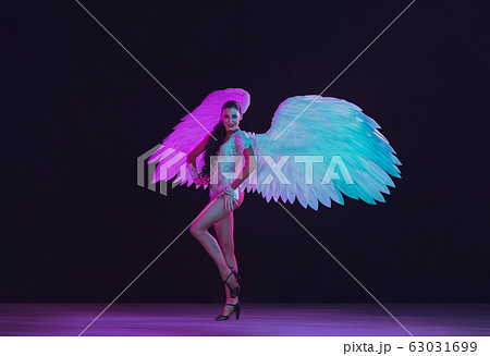 Young female dancer with angel's wings in neon light on black background 63031699