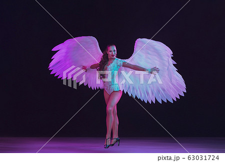 Young female dancer with angel's wings in neon light on black background 63031724
