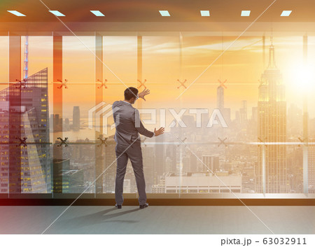 Businessman in front of office window thinking of new challenges Businessman in front of office window thinking of new challenges 63032911