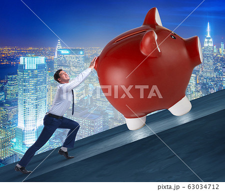 Man pushing piggybank uphill in business concept 63034712