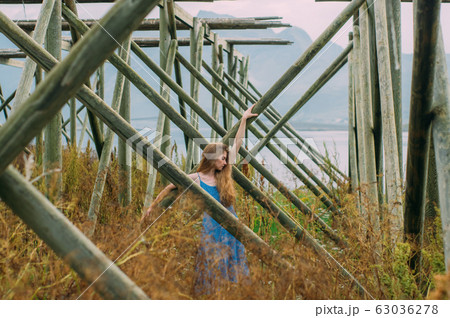 Young woman in blue dress holding tree trunk, Young woman in blue dress holding tree trunk, 63036278