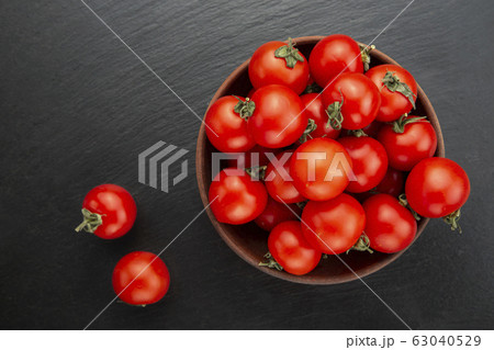 Fresh tomatoes in a bowl on a black background. Fresh tomatoes in a bowl on a black background. 63040529