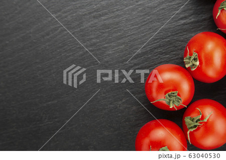 Fresh tomatoes on a black cutting board. Fresh tomatoes on a black cutting board. 63040530