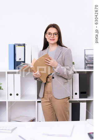 Young smiling businesswoman in smart casualwear holding collection of documents 63042670