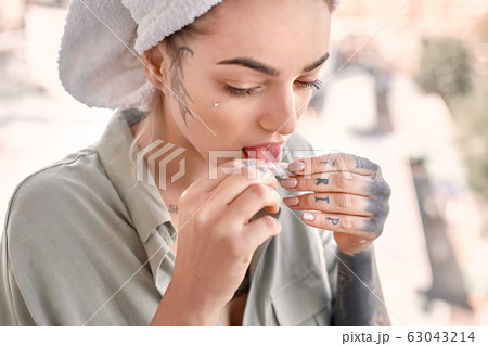 Young adult woman on balcony lick tobacco paper Young adult woman on balcony lick tobacco paper 63043214
