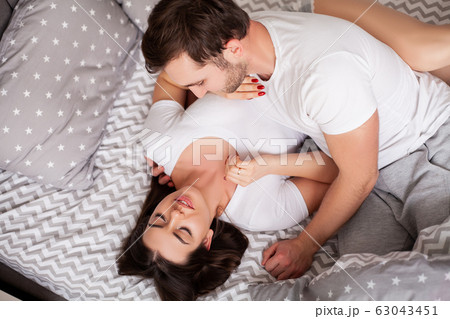 Happy sensual young couple lying in bed together. Happy sensual young couple lying in bed together. 63043451