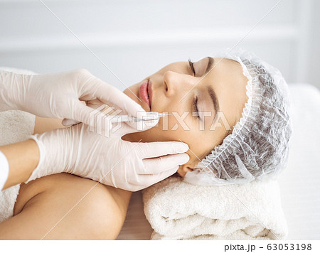 Beautician doing beauty procedure with syringe to face of young brunette woman. Cosmetic medicine and surgery, beauty injections Beautician doing beauty procedure with syringe to face of young brunette woman. Cosmetic medicine and surgery, beauty injections 63053198