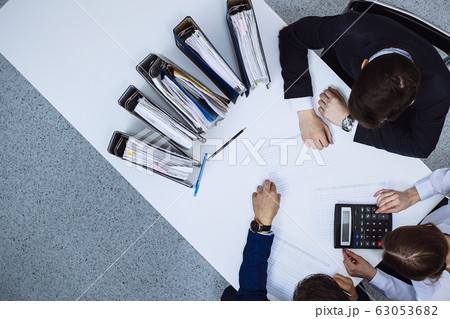 Business people at meeting, view from above. Bookkeeper or financial inspector making report, calculating or checking balance Business people at meeting, view from above. Bookkeeper or financial inspector making report, calculating or checking balance 63053682