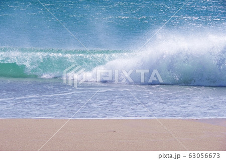 砂浜に叩きつけるように崩れる波 63056673