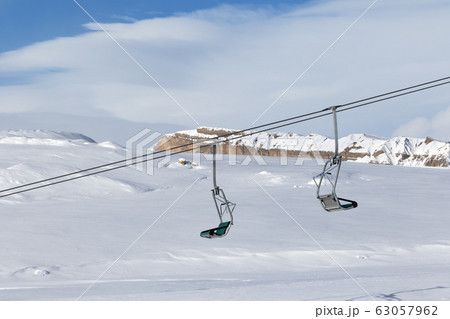 Snowy slope, chair-lift and blue sky with clouds 63057962