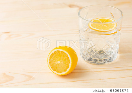 Glass of water with lemon on a wooden table, morning drink for a healthy lifestyle 63061372