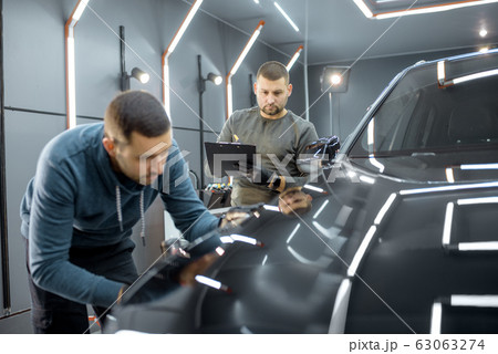 Workers examining vehicle body for scratches Workers examining vehicle body for scratches 63063274