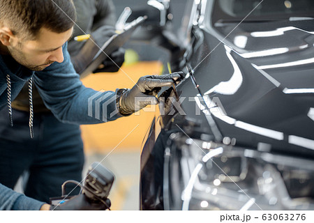 Worker examining vehicle body for scratches Worker examining vehicle body for scratches 63063276