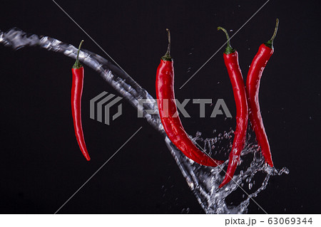 Cayenne peppers crossed with the stream of water. 63069344