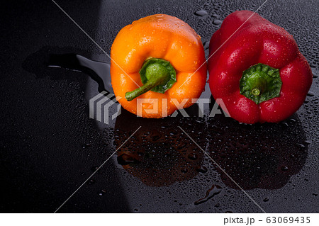 Two bulgarian peppers on wet surface. 63069435