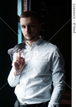 View in profile of a young businessman standing near the window 63069954