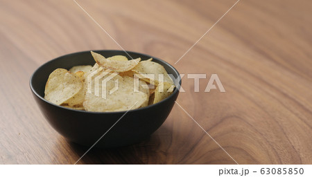 potato chips with black pepper in black bowl on walnut table potato chips with black pepper in black bowl on walnut table 63085850