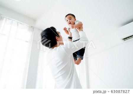 Asian father lifting his little own son up flying in the air Asian father lifting his little own son up flying in the air 63087827