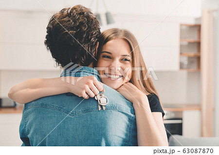 New home owners with keys, happy woman hugs 63087870