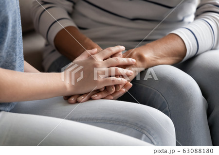 Close up of mature mom and daughter holding hands 63088180