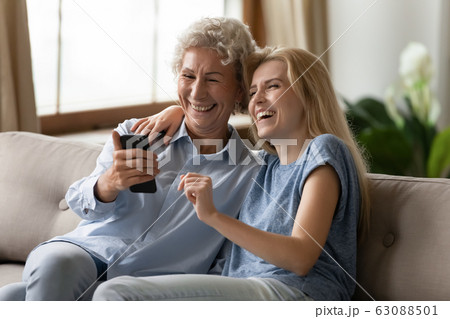 Smiling senior mom and adult daughter have fun using cellphone Smiling senior mom and adult daughter have fun using cellphone 63088501