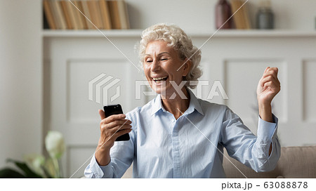 Overjoyed mature woman triumph reading good news on cell Overjoyed mature woman triumph reading good news on cell 63088878