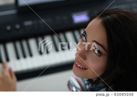 Woman turns around while playing electronic piano 63095036