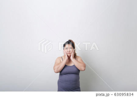 plump woman headache in exercise clothes 63095834