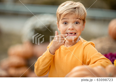 A close-up boy in a yellow sweater near the pumpkin crop. 63098723