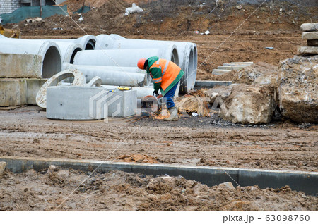 A builder worker in a helmet and a robe works A builder worker in a helmet and a robe works 63098760