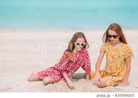 Two little happy girls have a lot of fun at tropical beach playing together  Stock Photo by travnikovstudio