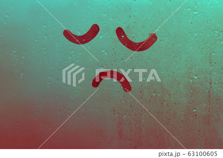 Foggy glass on window raindrops with drawn sad face eyes closed in green red gradient concept photo Foggy glass on window raindrops with drawn sad face eyes closed in green red gradient concept photo 63100605