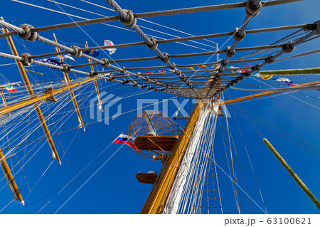 mast sailing ship with flags of Russia and other countries against the blue sky perspective view from below 63100621