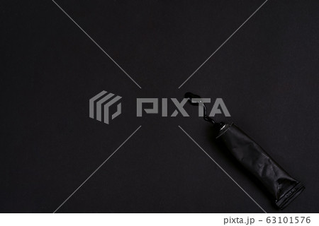 Black paint tin tube squeezed isolated on dark background. Top view. 63101576