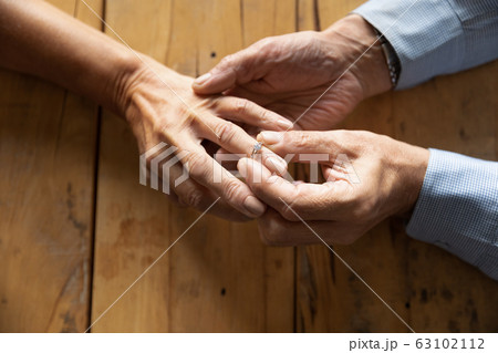 Old man put wedding ring on middle-aged woman hand Old man put wedding ring on middle-aged woman hand 63102112