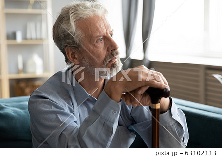 Unhappy old man with cane look in distance mourning 63102113
