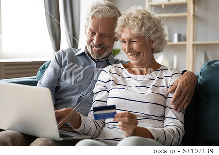Smiling 60s couple client shopping online using credit card 63102139