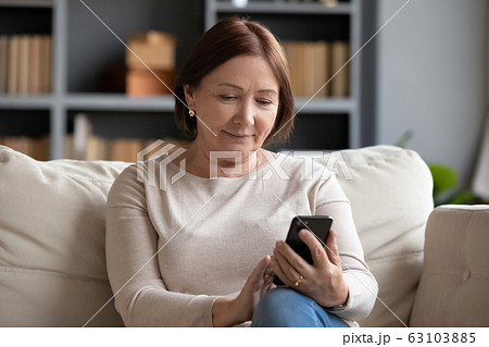 Pleasant senior older lady using applications on smartphone. Pleasant senior older lady using applications on smartphone. 63103885
