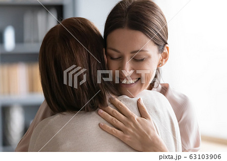 Affectionate young woman embracing middle aged brunette mother. 63103906