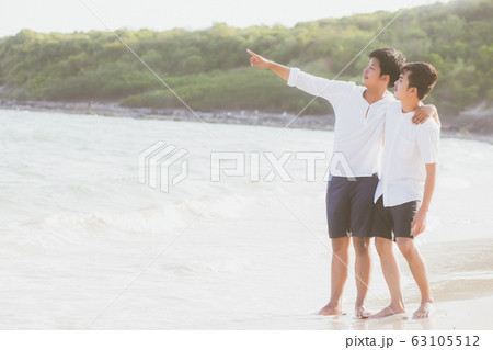 Homosexual portrait young asian couple standing pointing something together on beach in summer Homosexual portrait young asian couple standing pointing something together on beach in summer 63105512