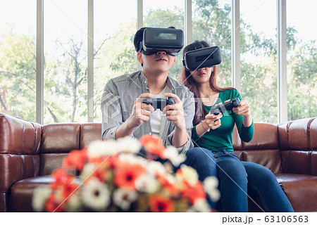 Young Couple Having Fun While Playing Virtual Reality Game Together in Their Home. 63106563