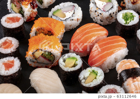 Large sushi set on black. An assortment of various maki, nigiri and rolls Large sushi set on black. An assortment of various maki, nigiri and rolls 63112646