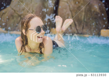 Young joyful woman under the water stream, pool, day spa, hot springs 63113930