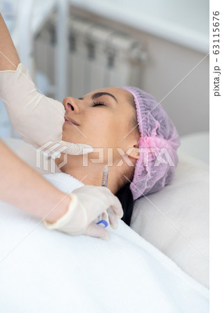Woman having injection in neck while having anti-aging procedures 63115676