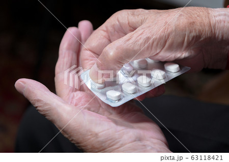 Hands of an old woman close-up. The old woman unpacks the tablets before use 63118421
