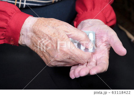 Hands of an old woman close-up. The old woman unpacks the tablets before use Hands of an old woman close-up. The old woman unpacks the tablets before use 63118422