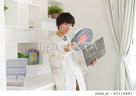 レコードジャケットとレコードを見る若い男性 63118881