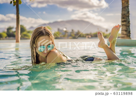 Luxury resort swimming pool. Beautiful woman tourist relaxing in holiday retreat on summer travel 63119898