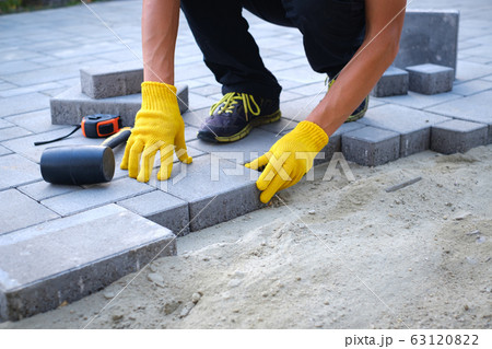 The master in yellow gloves lays paving stones 63120822